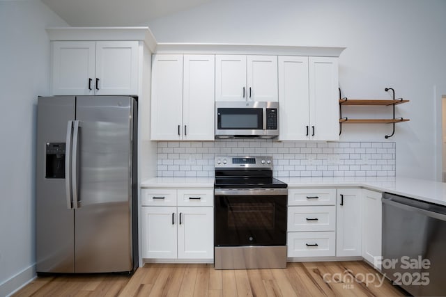 kitchen with stainless steel appliances, backsplash, white cabinets, and light wood-type flooring