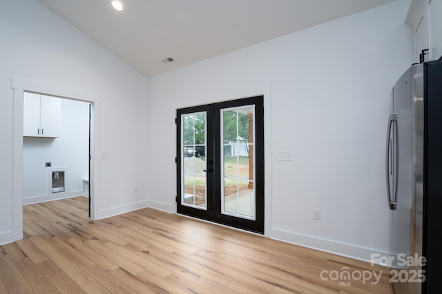 unfurnished room featuring french doors, high vaulted ceiling, and light hardwood / wood-style flooring