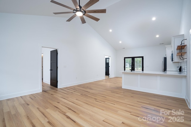 unfurnished living room with french doors, ceiling fan, high vaulted ceiling, and light hardwood / wood-style flooring