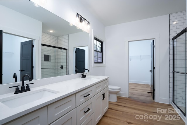 bathroom with vanity, hardwood / wood-style flooring, a shower with shower door, and toilet