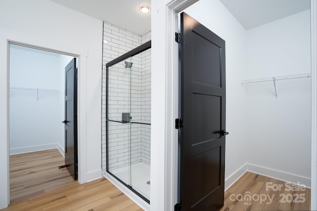 bathroom with hardwood / wood-style floors and a shower with shower door