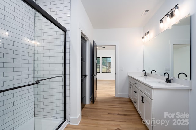 bathroom featuring wood-type flooring, a shower with shower door, and vanity