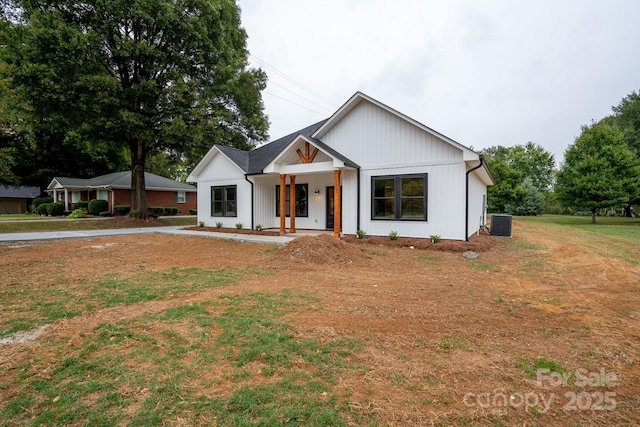 modern inspired farmhouse with a front yard, central air condition unit, and covered porch