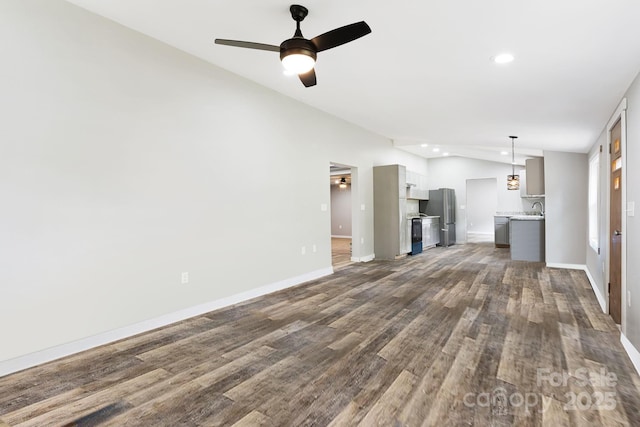 unfurnished living room with sink, dark wood-type flooring, vaulted ceiling, and ceiling fan