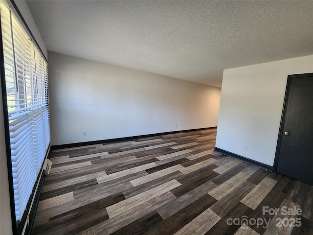 unfurnished room with dark wood-type flooring and a textured ceiling