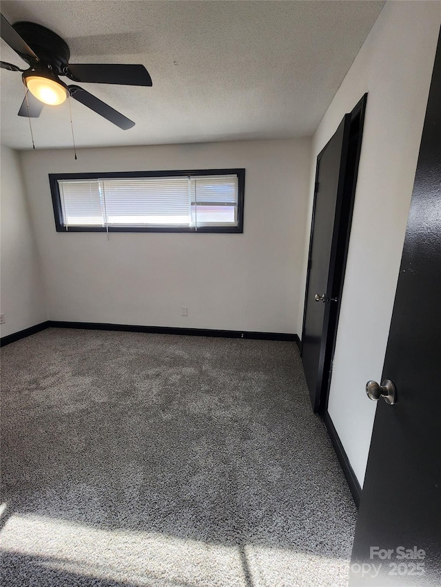 carpeted empty room featuring ceiling fan and a textured ceiling