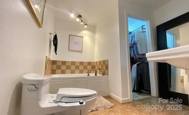 bathroom featuring tile patterned flooring, a tub, and track lighting