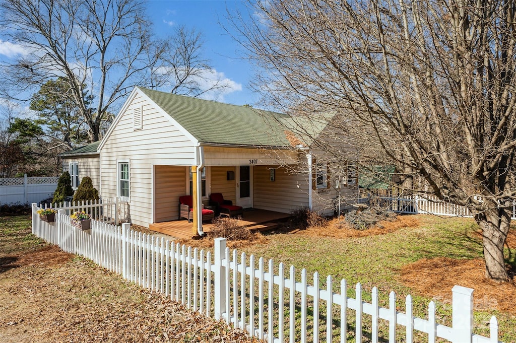 view of front of house with fence private yard, a front lawn, and roof with shingles