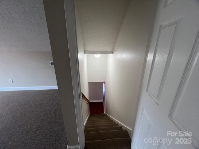 stairs featuring carpet and a textured ceiling