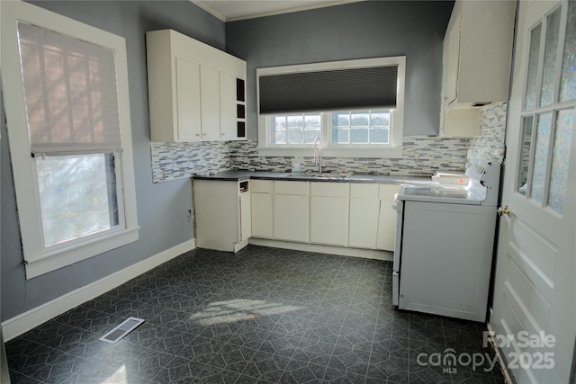 kitchen featuring white cabinetry, stove, sink, and a healthy amount of sunlight