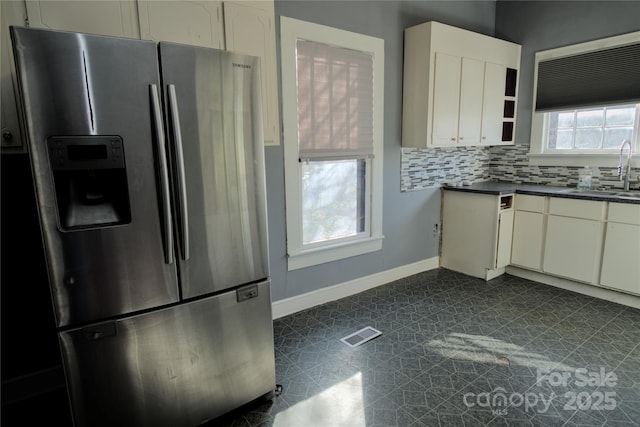 kitchen with sink, stainless steel fridge with ice dispenser, decorative backsplash, and a wealth of natural light