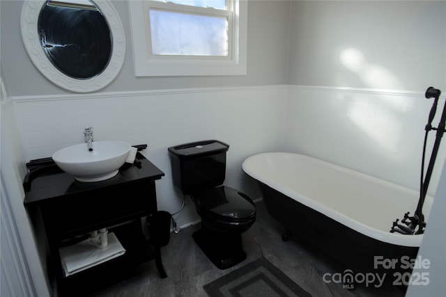 bathroom featuring vanity, toilet, tile walls, and a washtub