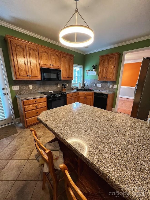 kitchen with decorative light fixtures, sink, black appliances, and tasteful backsplash