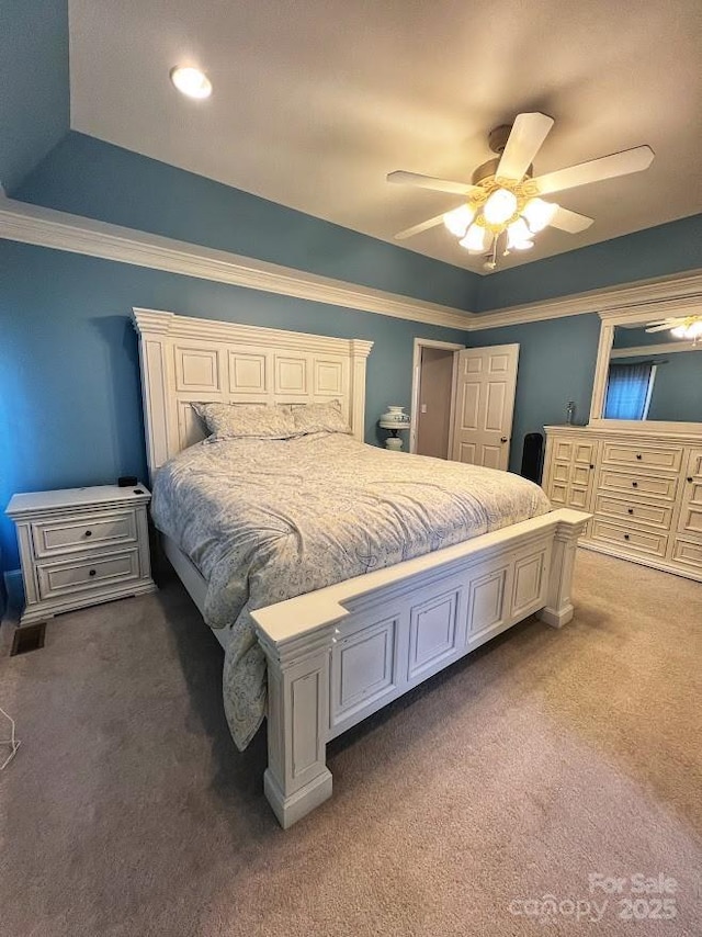 carpeted bedroom featuring ceiling fan and a tray ceiling