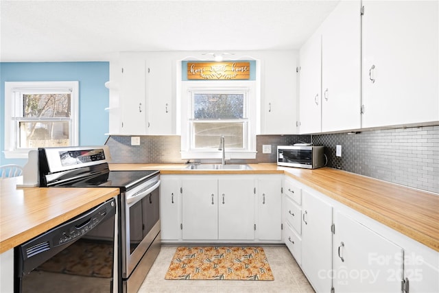 kitchen featuring sink, white cabinetry, stainless steel appliances, light tile patterned flooring, and decorative backsplash