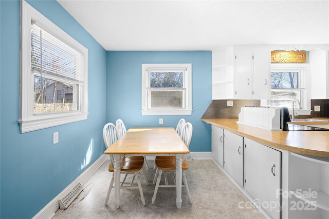 dining room with sink, a wealth of natural light, and light tile patterned flooring