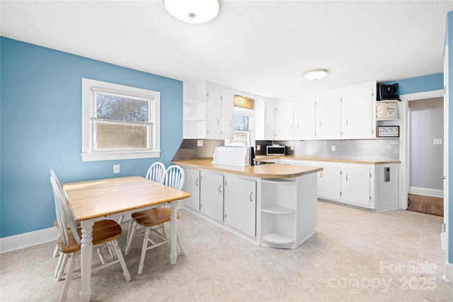 kitchen with white cabinetry, a wealth of natural light, kitchen peninsula, and tasteful backsplash