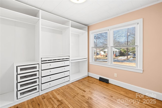 walk in closet with light hardwood / wood-style flooring