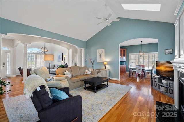 living room featuring vaulted ceiling, a healthy amount of sunlight, and decorative columns