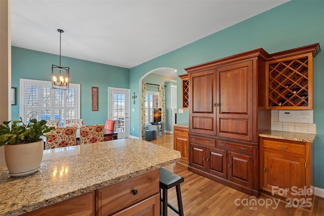 kitchen featuring hanging light fixtures, light stone countertops, a breakfast bar area, and light hardwood / wood-style floors