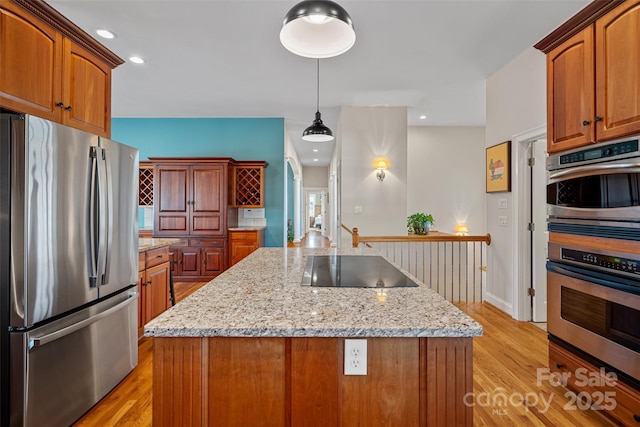 kitchen featuring light wood-type flooring, stainless steel appliances, light stone counters, and a kitchen island