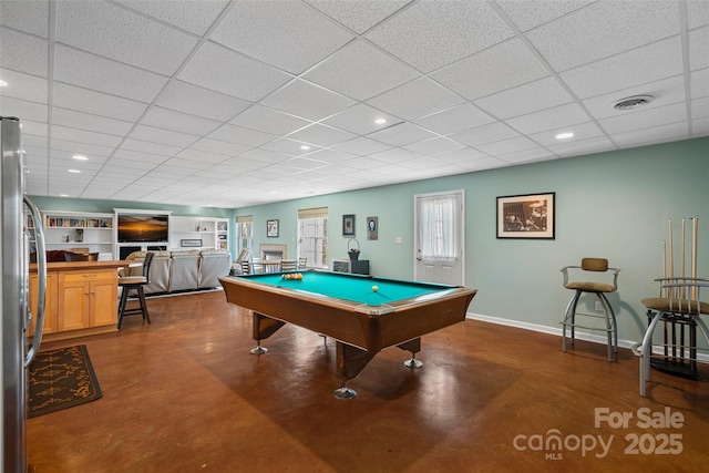 recreation room with concrete floors, pool table, built in features, and a paneled ceiling