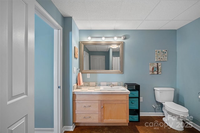 bathroom with toilet, vanity, and a paneled ceiling