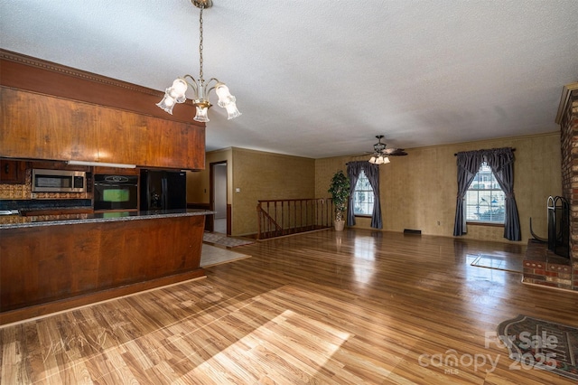 kitchen with black appliances, light hardwood / wood-style floors, a textured ceiling, pendant lighting, and ceiling fan with notable chandelier