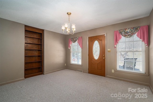 entrance foyer featuring an inviting chandelier, plenty of natural light, light carpet, and a textured ceiling