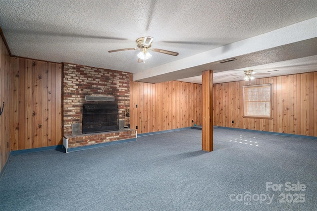 basement featuring a fireplace, wood walls, and a textured ceiling