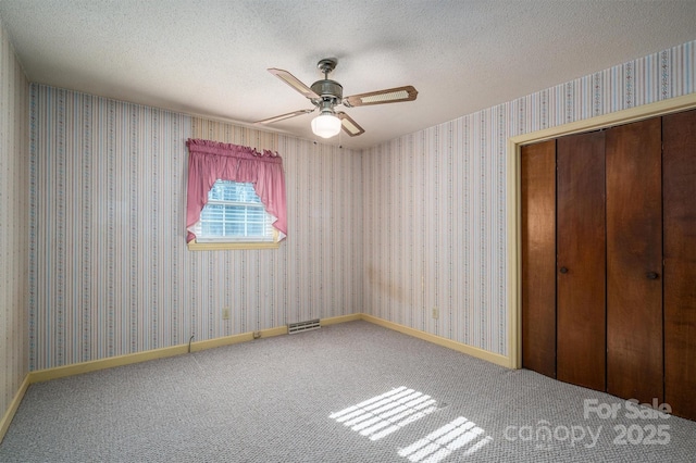 unfurnished bedroom with a textured ceiling, carpet floors, a closet, and ceiling fan