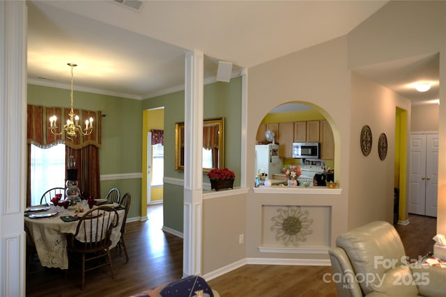 dining area with dark hardwood / wood-style flooring, ornamental molding, and a chandelier