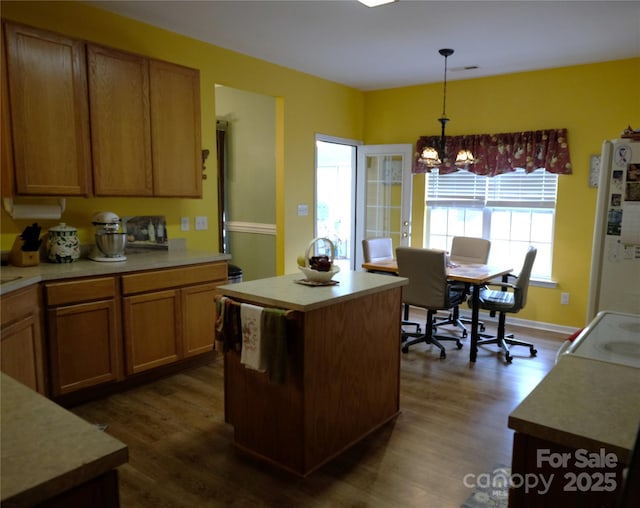 kitchen with white fridge, dark wood-type flooring, decorative light fixtures, and a center island