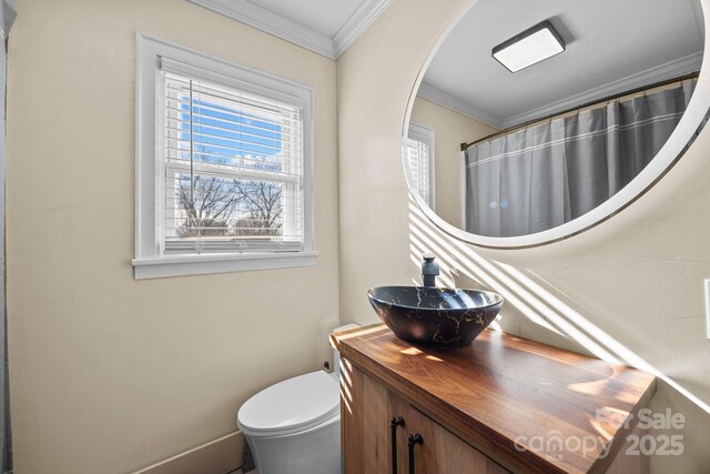 bathroom with vanity, toilet, a healthy amount of sunlight, and crown molding