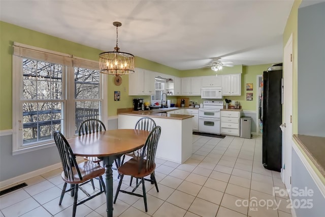 tiled dining space with sink and ceiling fan with notable chandelier