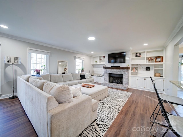 living room featuring dark wood-type flooring, a fireplace, and crown molding