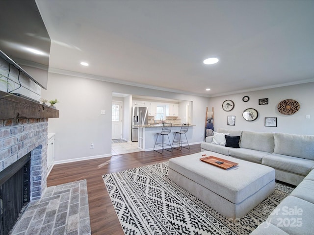 living room featuring a brick fireplace, crown molding, and hardwood / wood-style floors