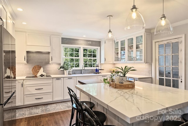 kitchen with hanging light fixtures, a kitchen island, white cabinets, a breakfast bar, and sink