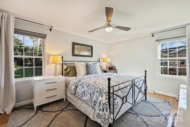 bedroom with ceiling fan, multiple windows, dark hardwood / wood-style floors, and ornamental molding