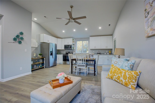 living room with ceiling fan, lofted ceiling, and light hardwood / wood-style floors