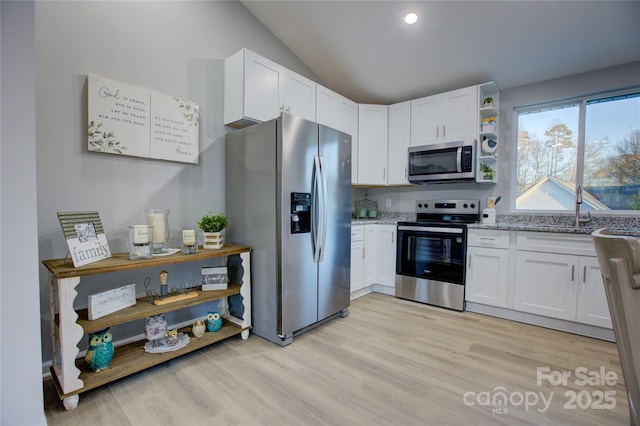 kitchen with light wood-type flooring, stainless steel appliances, white cabinets, and light stone counters