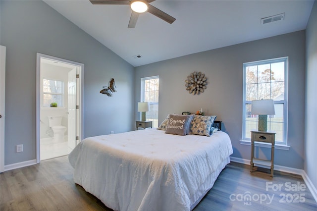 bedroom with ceiling fan, multiple windows, hardwood / wood-style floors, and ensuite bathroom