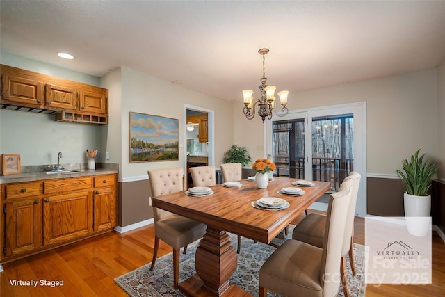 dining space featuring light wood-type flooring, wet bar, and a notable chandelier