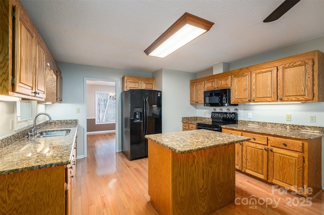 kitchen with sink, a kitchen island, light hardwood / wood-style floors, and black appliances