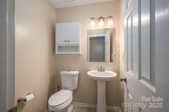 bathroom featuring toilet, tile patterned flooring, and a textured ceiling