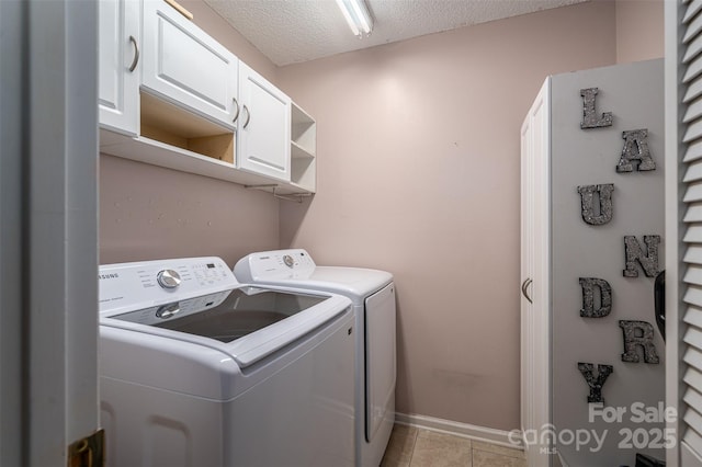 washroom with cabinets, independent washer and dryer, light tile patterned flooring, and a textured ceiling