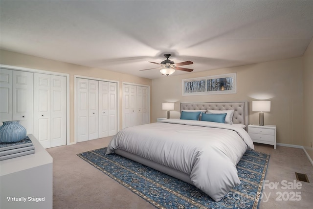 bedroom with ceiling fan, carpet floors, and two closets