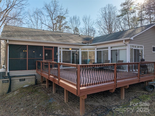 rear view of house featuring a wooden deck and a sunroom