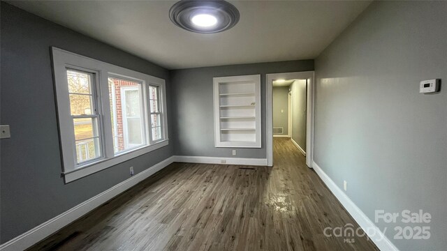 spare room with wood-type flooring and built in features