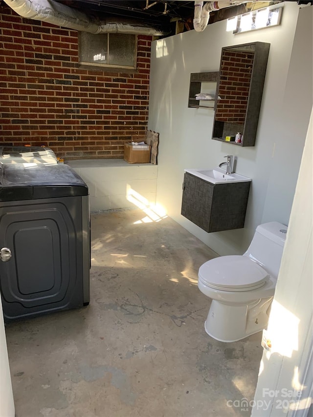 basement with brick wall, sink, and separate washer and dryer